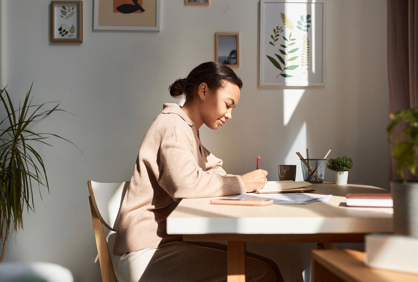 Person writing in a notebook at home with sunlight