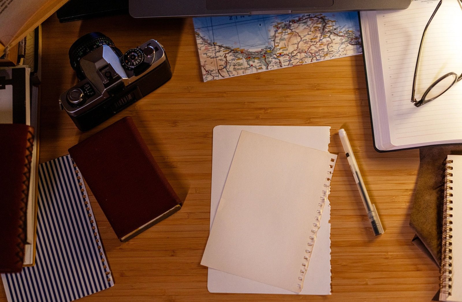 High angle view of a creative workspace with laptop, vintage camera, and map