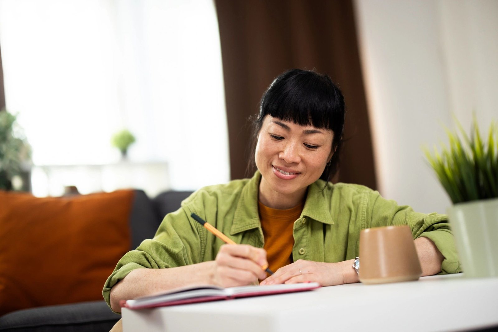 Woman writing in notebook at home